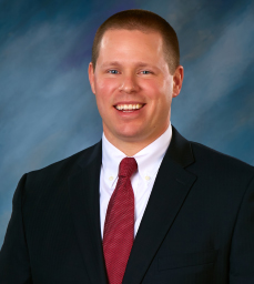 man smiling wearing a suit with red tie